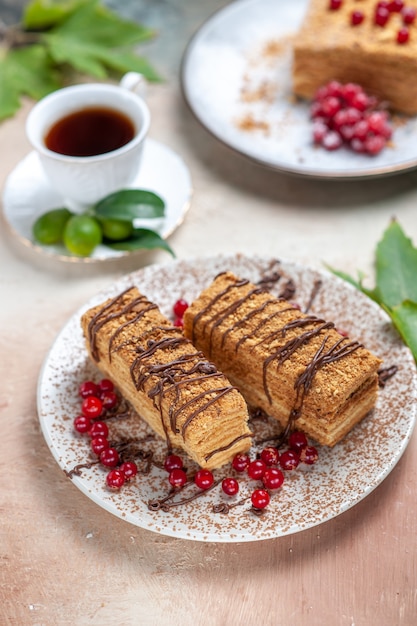 Rebanada de pastel delicioso vista frontal con té y bayas en la luz