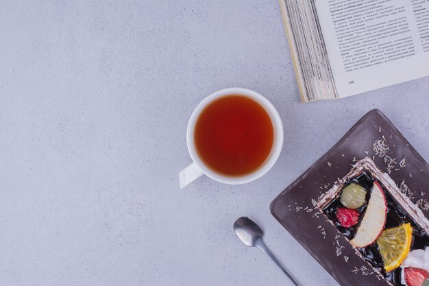 Una rebanada de pastel de frutas de chocolate con una taza de té, vista superior