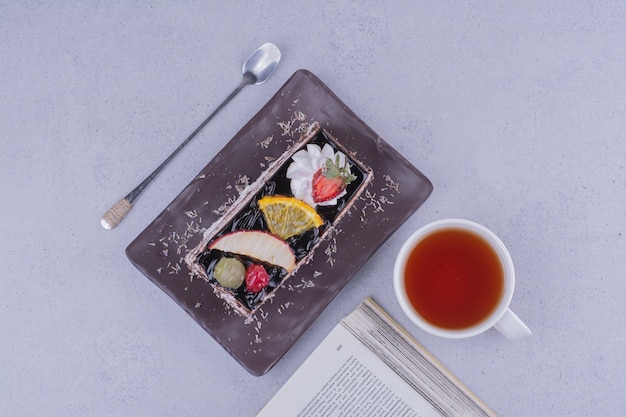 Una rebanada de pastel de frutas de chocolate con una taza de té, vista superior