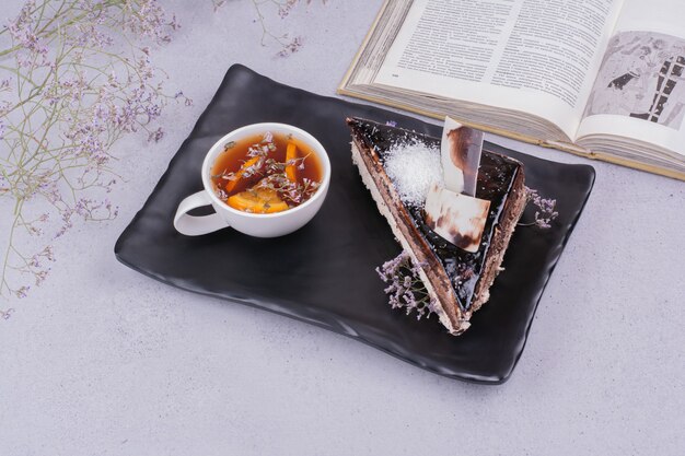 Una rebanada de pastel de ganache de chocolate con una taza de té de hierbas.