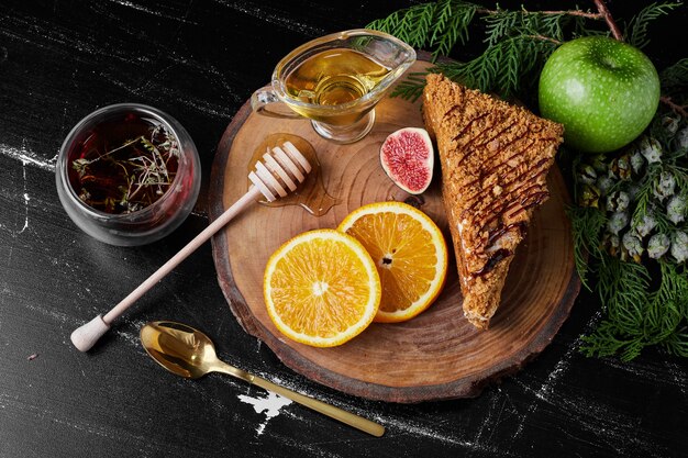 Una rebanada de pastel de miel con rodajas de naranja y té de hierbas.