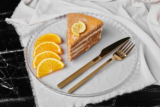 Una rebanada de pastel de miel con rodajas de naranja.
