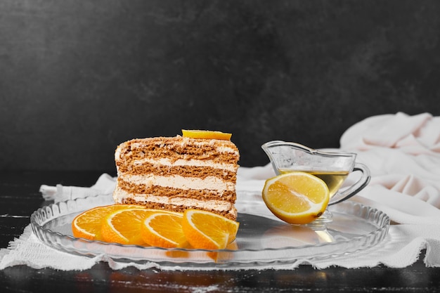 Una rebanada de pastel de miel con rodajas de naranja.