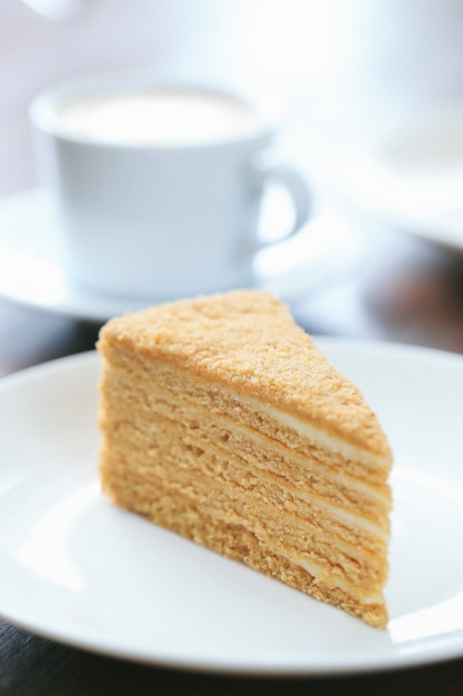 Una rebanada de pastel de miel con una taza de leche.