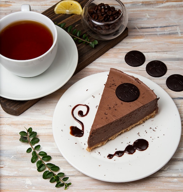 Una rebanada de pastel de queso cheesecake con chips de chocolate y una taza de té.