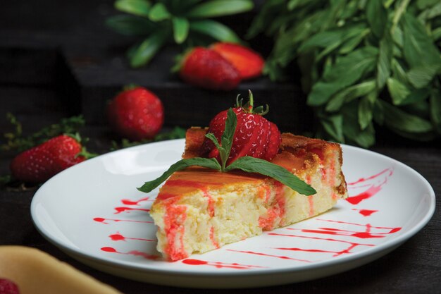 Rebanada de pastel de queso con hojas de fresa y menta