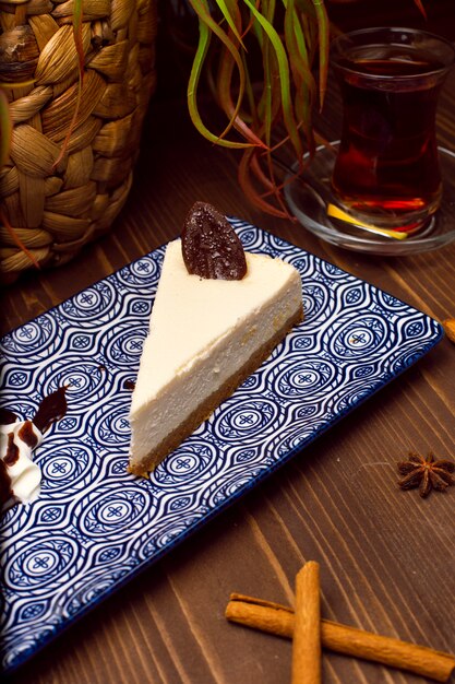 Rebanada de pastel de queso de vainilla en un plato contra una mesa rústica de madera marrón