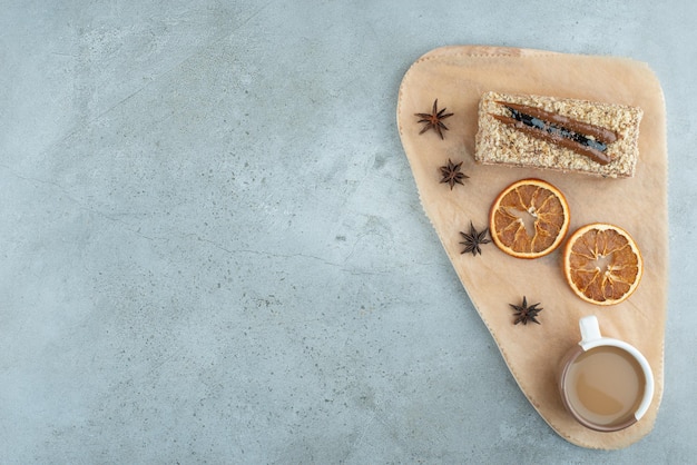 Rebanada de pastel con rodajas de naranja y café sobre tabla de madera. Foto de alta calidad