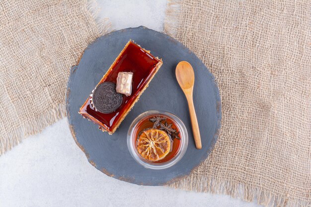 Rebanada de pastel, vaso de té y cuchara en tablero oscuro. Foto de alta calidad