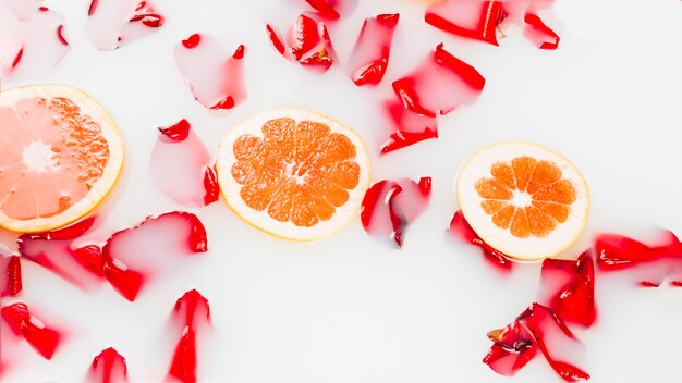 Rebanada de pomelos y pétalos de flores flotando en la leche