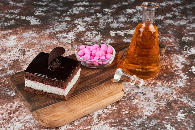 Una rebanada de tarta de chocolate con una botella de bebida y caramelos.