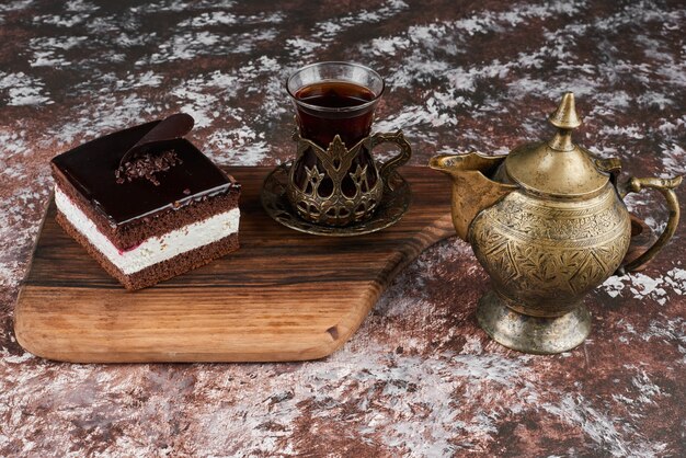 Una rebanada de tarta de chocolate con un vaso de té.