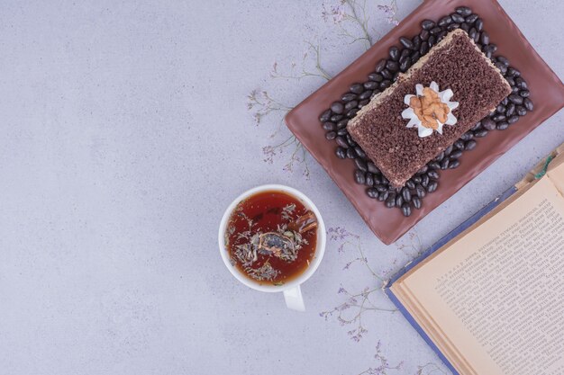Una rebanada de tarta medovic con chocolate picado en un plato con una taza de té de hierbas