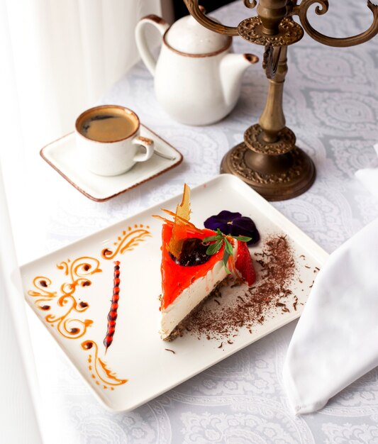 Una rebanada de tarta de queso con fresas adornada con trozos de fresa y chocolate