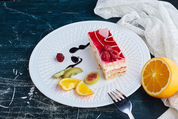 Rebanada de tarta de queso con sirope de frambuesa en un plato blanco.