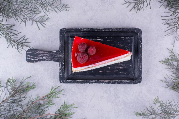 Rebanada de tarta de queso en tablero negro con rama de pino. Foto de alta calidad