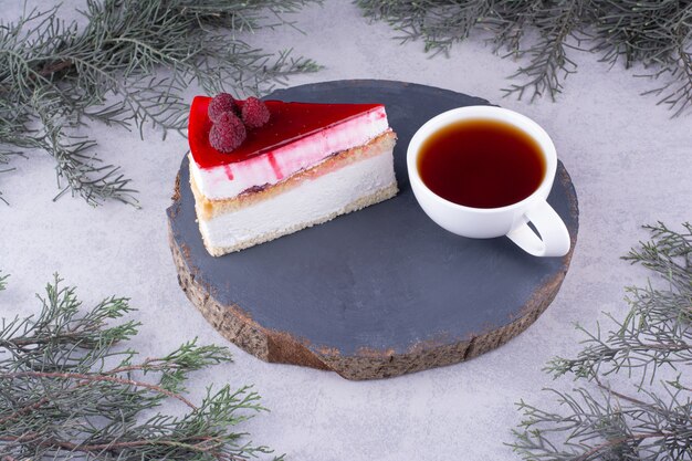 Rebanada de tarta de queso con taza de té en pieza de madera. Foto de alta calidad