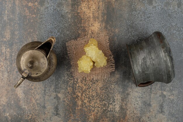 Rebanadas de azúcar dulce amarillo con dos hervidores antiguos en la pared de mármol