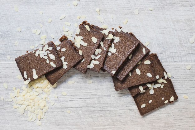 Foto gratuita rebanadas de barras de chocolate y almendras sobre fondo blanco con textura de madera