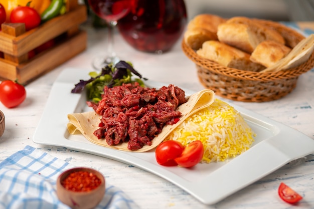 Rebanadas de carne de bbq a la parrilla, doner en lavash con ensalada verde, tomates y guarnición de arroz