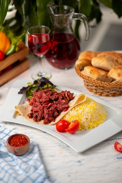 Rebanadas de carne de bbq a la parrilla, doner en lavash con ensalada verde, tomates y guarnición de arroz