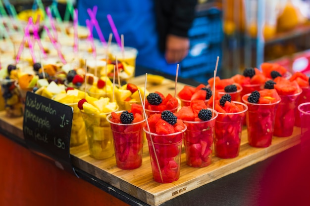 Rebanadas de fruta fresca en el vaso desechable de plástico para la venta