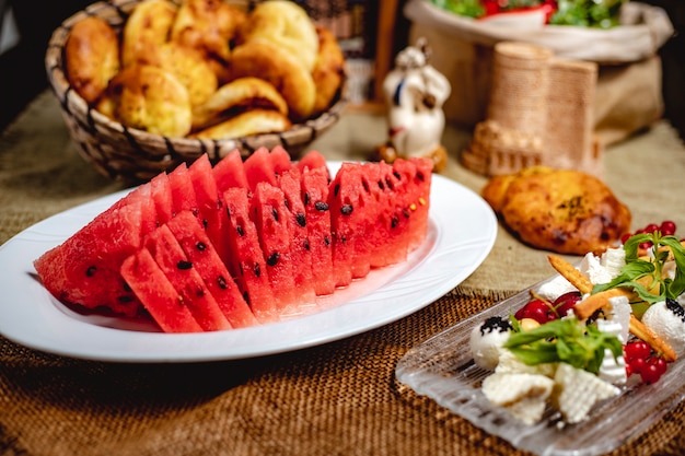 Rebanadas de fruta de sandía servida con queso blanco sobre la mesa