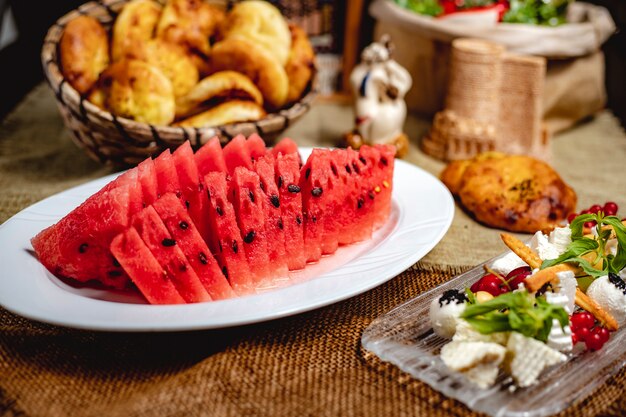 Rebanadas de fruta de sandía servida con queso blanco sobre la mesa