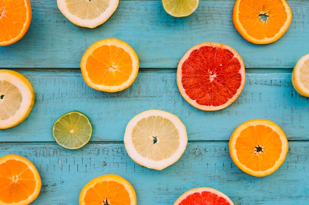 Rebanadas de frutas cítricas jugosas frescas en tablón de madera azul