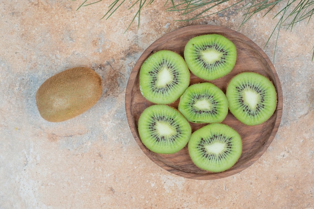 Rebanadas de kiwi fresco en placa de madera.