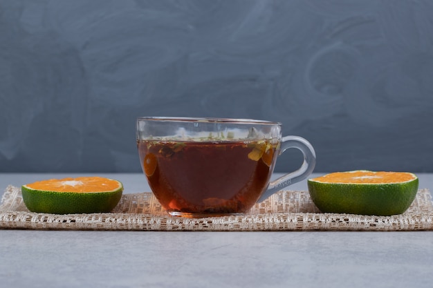 Rebanadas de mandarinas y taza de té negro sobre mesa de mármol. Foto de alta calidad