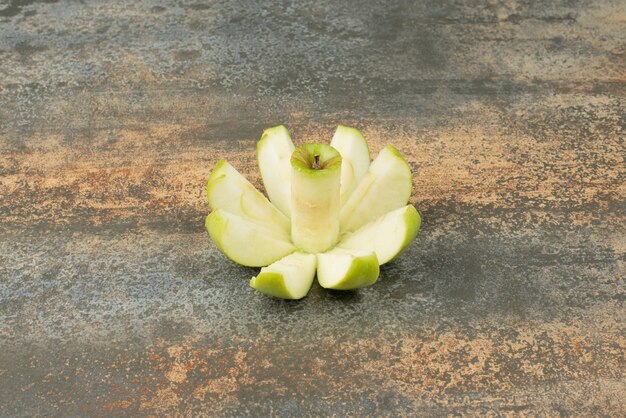 Rebanadas de manzana verde sobre superficie de mármol.