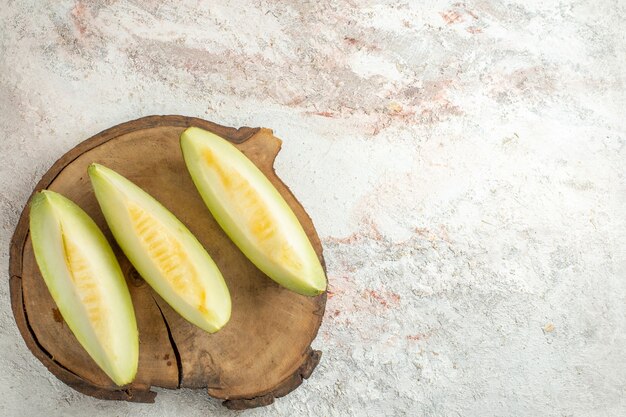 Rebanadas de melón en placa de madera en la esquina derecha de mármol