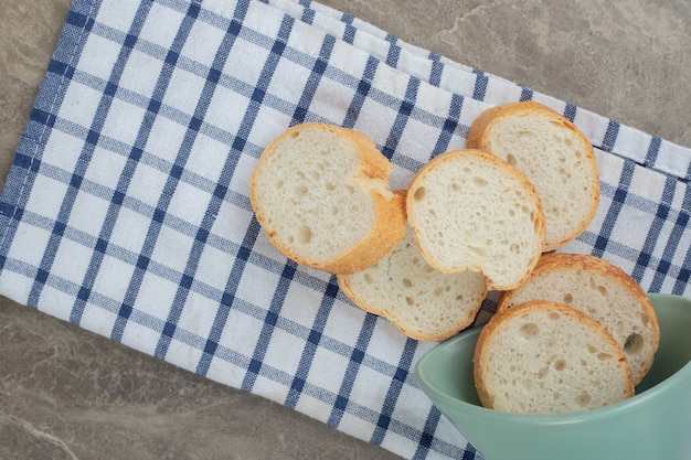 Rebanadas de pan baguette de un tazón sobre un mantel. Foto de alta calidad