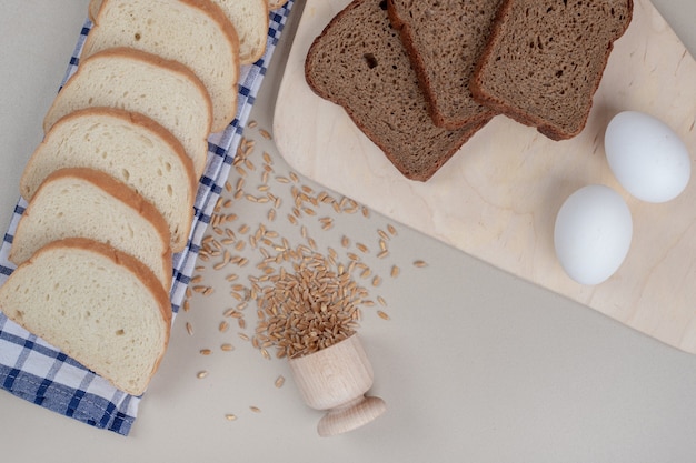 Rebanadas de pan blanco y marrón fresco con huevos y grano de avena