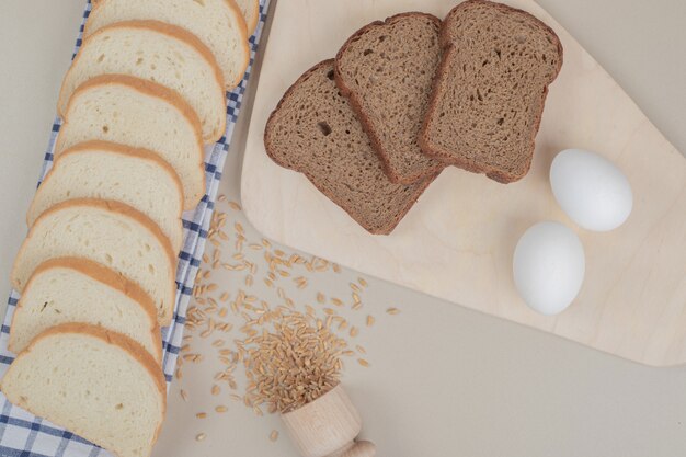 Rebanadas de pan blanco y marrón fresco con huevos sobre un mantel