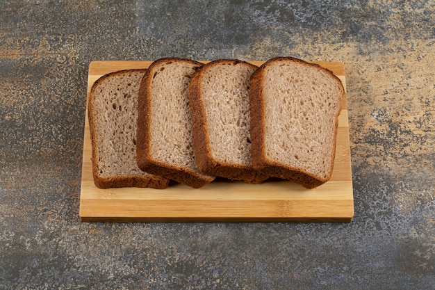 Foto gratuita rebanadas de pan de centeno fresco sobre tabla de madera.