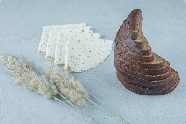 Rebanadas de pan de centeno y lavash sobre la superficie de piedra con trigo