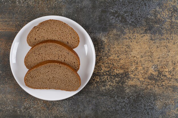 Rebanadas de pan de centeno negro en la placa blanca.