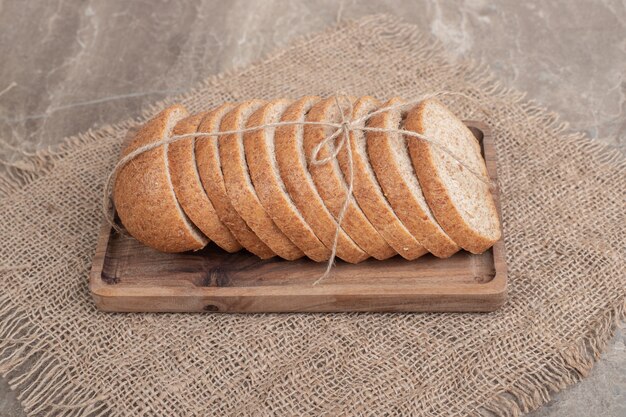 Rebanadas de pan de centeno en placa de madera con arpillera. Foto de alta calidad