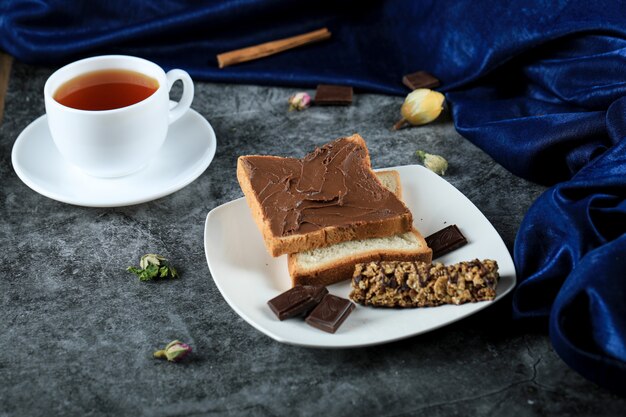 Rebanadas de pan con crema de chocolate y una taza de té.