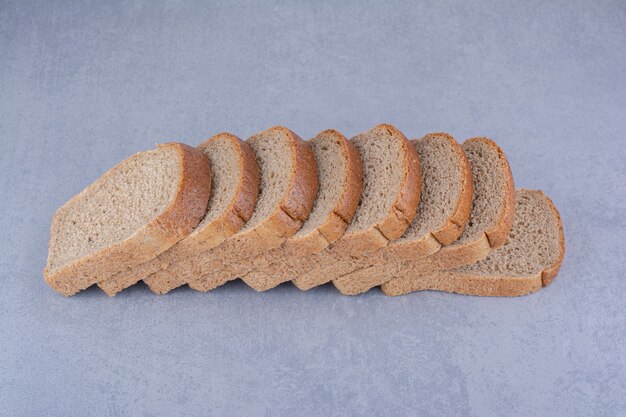 Rebanadas de pan dietético alineadas sobre la superficie de mármol