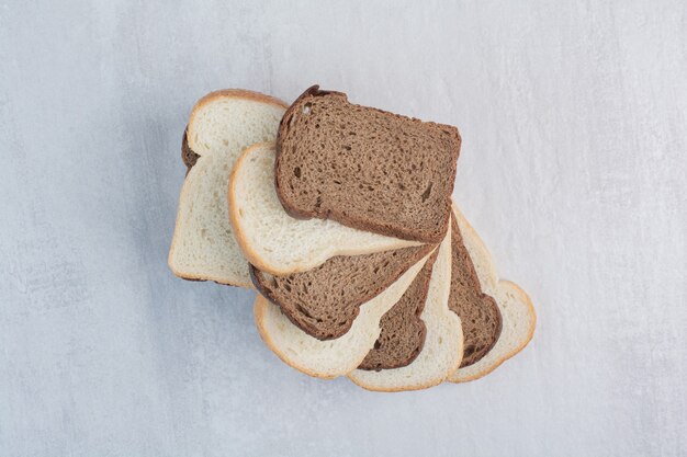 Rebanadas de pan fresco blanco y marrón sobre fondo de mármol.