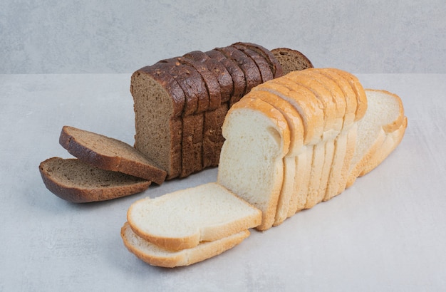 Rebanadas de pan fresco blanco y marrón sobre fondo de mármol.