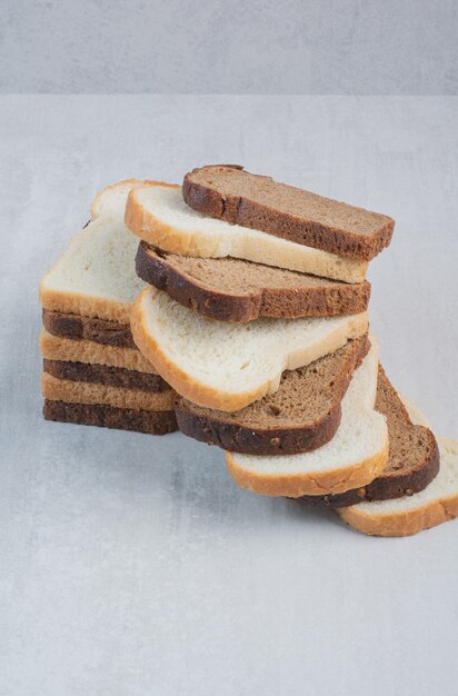 Rebanadas de pan fresco blanco y marrón sobre fondo de mármol.