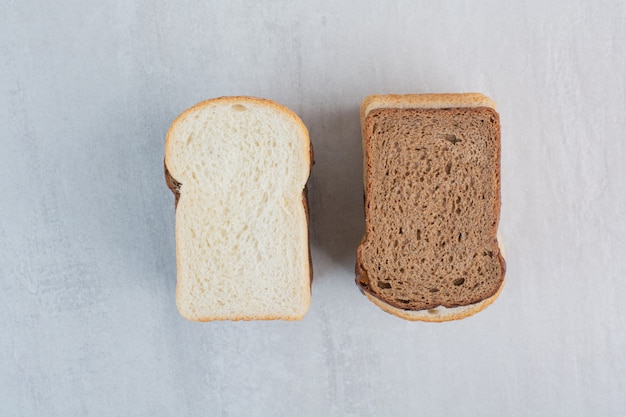 Rebanadas de pan fresco blanco y marrón sobre fondo de mármol.