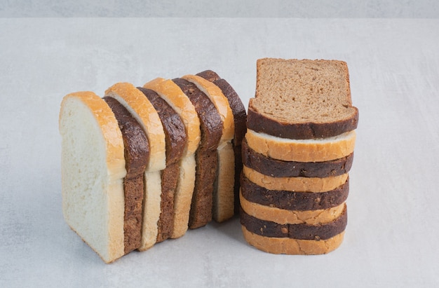 Rebanadas de pan fresco blanco y marrón sobre fondo de mármol.