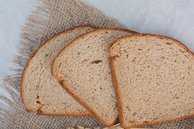 Rebanadas de pan fresco marrón sobre fondo de mármol.