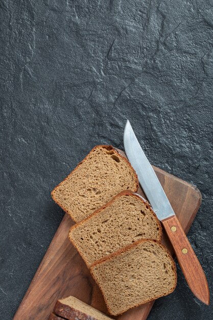 Rebanadas de pan integral con un cuchillo sobre una tabla de madera