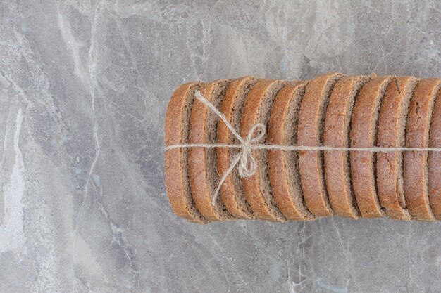 Rebanadas de pan integral en cuerda sobre superficie de mármol